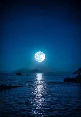 Gece ve ay sakin deniz suyunda küçük tekne manzara görünümü.