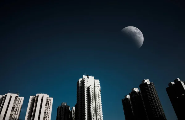 Paisaje urbano por la noche y cielo oscuro con media luna . — Foto de Stock