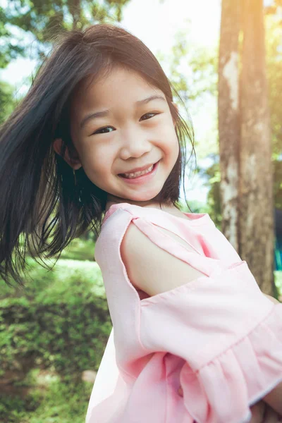Portrét usměvavé malé asijské dívky v parku. — Stock fotografie