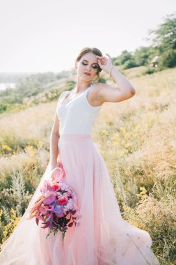 Şatafatlı beyaz ve pembe gelinlikli gelin gün batımında doğada