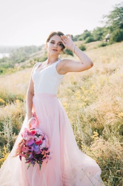 Şatafatlı beyaz ve pembe gelinlikli gelin gün batımında doğada
