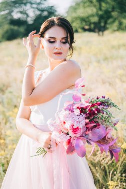 Şatafatlı beyaz ve pembe gelinlikli gelin gün batımında doğada
