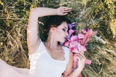 Şatafatlı beyaz ve pembe gelinlikli gelin gün batımında doğada