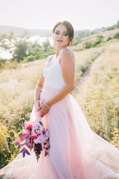 日落时穿着华丽的白色和粉色婚纱的新娘 — 图库照片