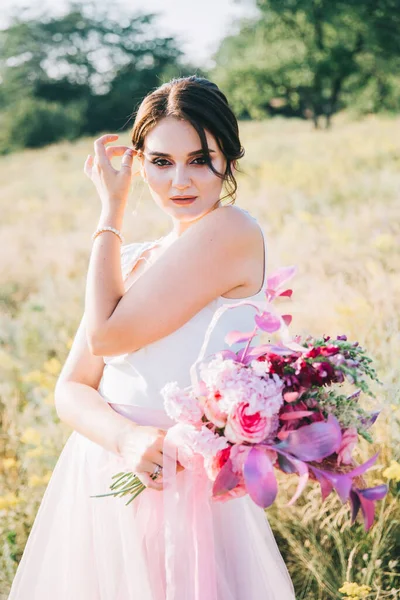 夕日で自然の中で豪華な白とピンクのウェディングドレスで花嫁 — ストック写真