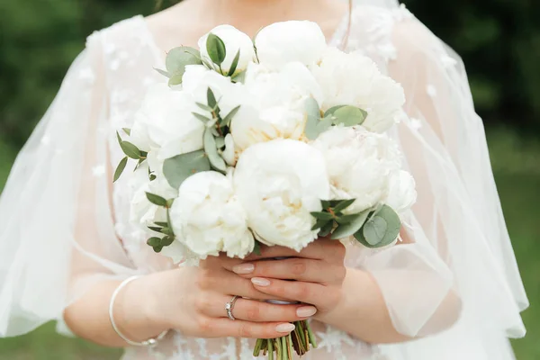luxurious bouquet in the hands of the bride in a wedding dress and veil, rings