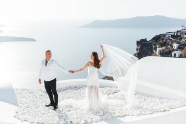Yunanistan 'ın Santorini adasında düğün, güzel bir çift, beyaz gelinlik içinde gelin. Beyaz evler ve mavi gökyüzü