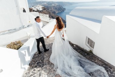 Yunanistan 'ın Santorini adasında düğün, güzel bir çift, beyaz gelinlik içinde gelin. Beyaz evler ve mavi gökyüzü