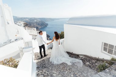 Yunanistan 'ın Santorini adasında düğün, güzel bir çift, beyaz gelinlik içinde gelin. Beyaz evler ve mavi gökyüzü