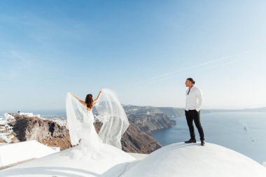 Yunanistan 'ın Santorini adasında düğün, güzel bir çift, beyaz gelinlik içinde gelin. Beyaz evler ve mavi gökyüzü