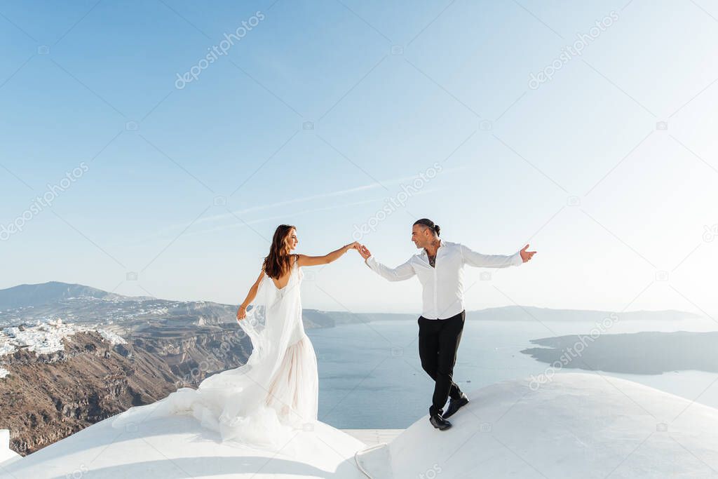 Wedding on Santorini island in Greece, beautiful couple, bride in a white wedding dress. White houses and blue sky