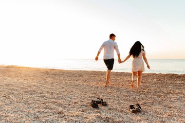 Balayı sırasında beyaz elbiseli sevimli bir çift kumsalda yürür bir fotoşop aşk hikayesi, okyanus kıyısında, plajda