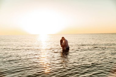 Balayı sırasında beyaz elbiseli sevimli bir çift kumsalda yürür bir fotoşop aşk hikayesi, okyanus kıyısında, plajda