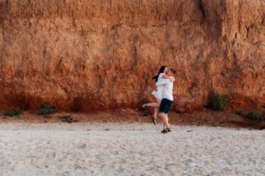 Balayı sırasında beyaz elbiseli sevimli bir çift kumsalda yürür bir fotoşop aşk hikayesi, okyanus kıyısında, plajda