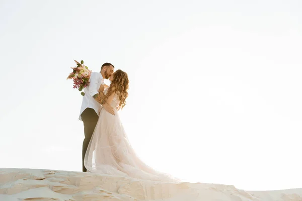 Güzel bir çiftin aşk hikayesi. Pembe bir gelinlik içinde Sahra Çölü 'nde bir buketi olan kumlar ve kumullar.