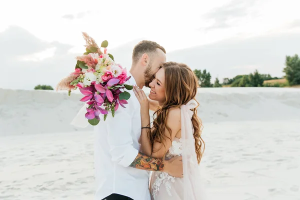 Güzel bir çiftin aşk hikayesi. Pembe bir gelinlik içinde Sahra Çölü 'nde bir buketi olan kumlar ve kumullar.