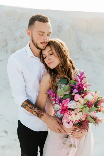 Güzel bir çiftin aşk hikayesi. Pembe bir gelinlik içinde Sahra Çölü 'nde bir buketi olan kumlar ve kumullar.