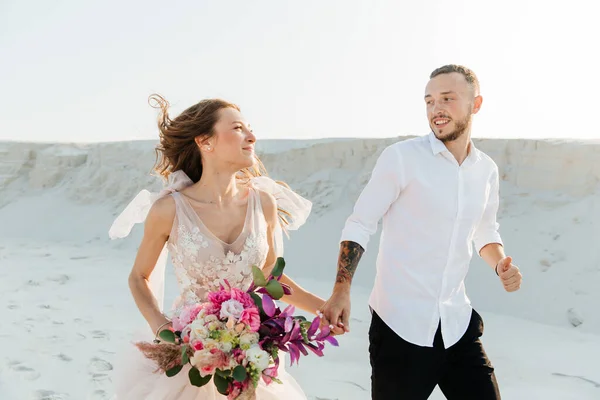 Güzel bir çiftin aşk hikayesi. Pembe bir gelinlik içinde Sahra Çölü 'nde bir buketi olan kumlar ve kumullar.