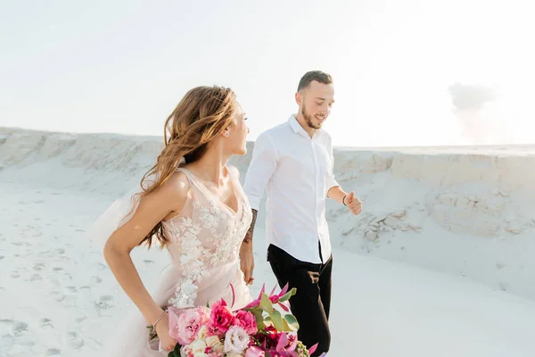サハラ砂漠 砂丘で花束とピンクの結婚式の豪華なドレスで美しいカップルの愛の物語 — ストック写真