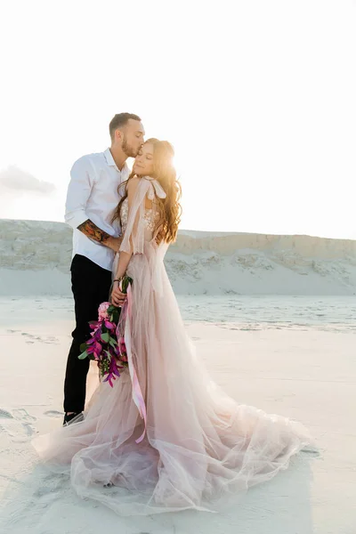 Güzel bir çiftin aşk hikayesi. Pembe bir gelinlik içinde Sahra Çölü 'nde bir buketi olan kumlar ve kumullar.