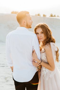 Güzel bir çiftin aşk hikayesi. Pembe bir gelinlik içinde Sahra Çölü 'nde bir buketi olan kumlar ve kumullar.