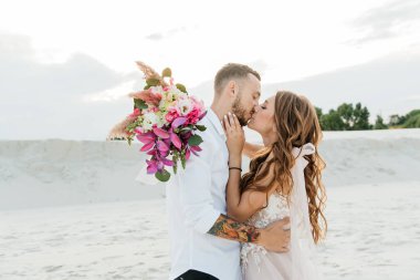 Güzel bir çiftin aşk hikayesi. Pembe bir gelinlik içinde Sahra Çölü 'nde bir buketi olan kumlar ve kumullar.