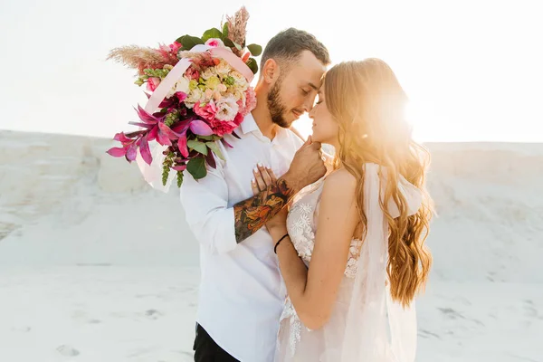 Güzel bir çiftin aşk hikayesi. Pembe bir gelinlik içinde Sahra Çölü 'nde bir buketi olan kumlar ve kumullar.