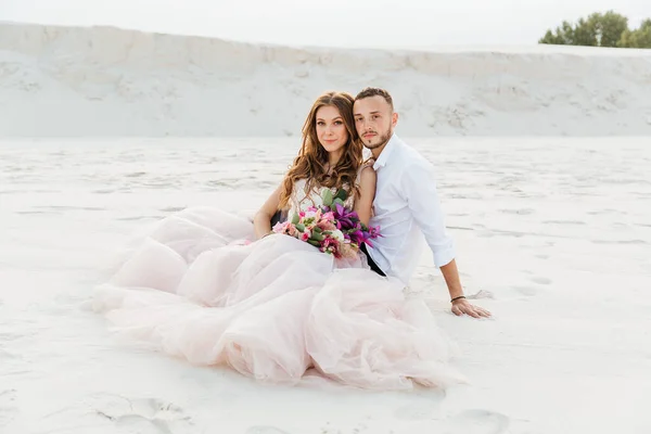 Güzel bir çiftin aşk hikayesi. Pembe bir gelinlik içinde Sahra Çölü 'nde bir buketi olan kumlar ve kumullar.