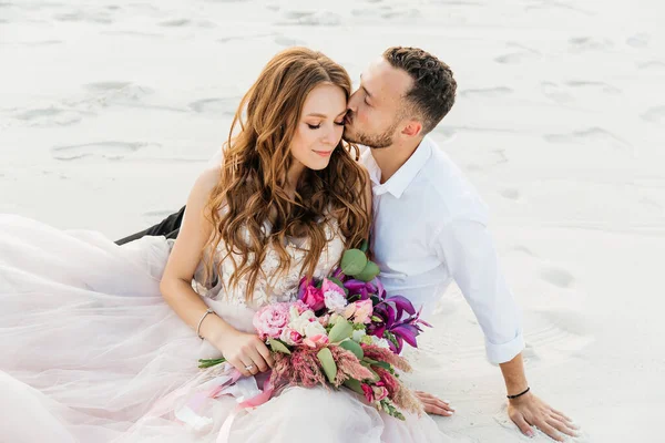 Güzel bir çiftin aşk hikayesi. Pembe bir gelinlik içinde Sahra Çölü 'nde bir buketi olan kumlar ve kumullar.