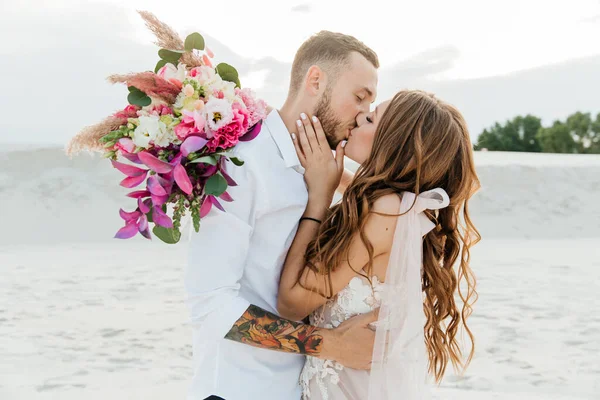 Güzel bir çiftin aşk hikayesi. Pembe bir gelinlik içinde Sahra Çölü 'nde bir buketi olan kumlar ve kumullar.