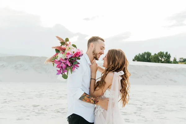 Güzel bir çiftin aşk hikayesi. Pembe bir gelinlik içinde Sahra Çölü 'nde bir buketi olan kumlar ve kumullar.