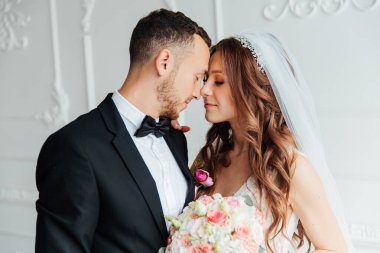 Damadın siyah takım elbiseli ilk buluşması ve beyaz gelinlikli gelinin beyaz ve siyah arka planda bir fotoğraf stüdyosunun içinde bir buket olması.