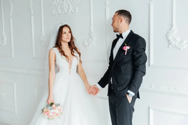 Damadın siyah takım elbiseli ilk buluşması ve beyaz gelinlikli gelinin beyaz ve siyah arka planda bir fotoğraf stüdyosunun içinde bir buket olması.