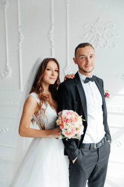 Damadın siyah takım elbiseli ilk buluşması ve beyaz gelinlikli gelinin beyaz ve siyah arka planda bir fotoğraf stüdyosunun içinde bir buket olması.