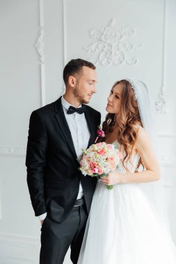 Damadın siyah takım elbiseli ilk buluşması ve beyaz gelinlikli gelinin beyaz ve siyah arka planda bir fotoğraf stüdyosunun içinde bir buket olması.