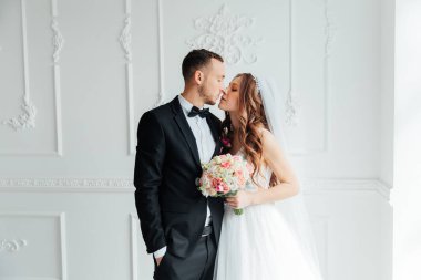 Damadın siyah takım elbiseli ilk buluşması ve beyaz gelinlikli gelinin beyaz ve siyah arka planda bir fotoğraf stüdyosunun içinde bir buket olması.