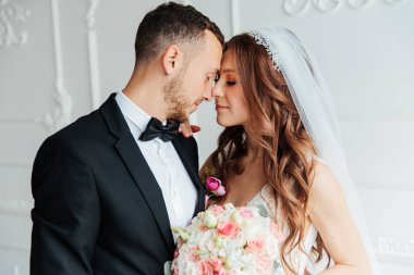 Damadın siyah takım elbiseli ilk buluşması ve beyaz gelinlikli gelinin beyaz ve siyah arka planda bir fotoğraf stüdyosunun içinde bir buket olması.