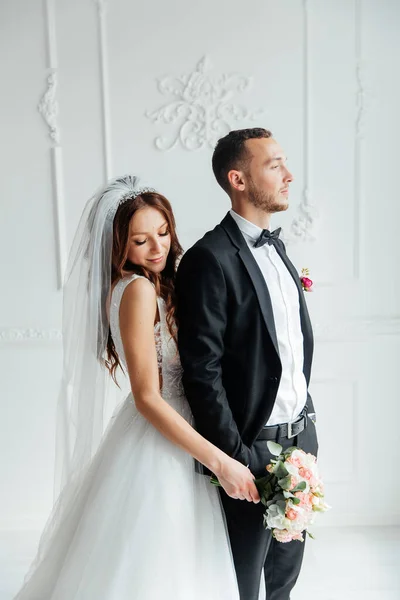 Damadın siyah takım elbiseli ilk buluşması ve beyaz gelinlikli gelinin beyaz ve siyah arka planda bir fotoğraf stüdyosunun içinde bir buket olması.