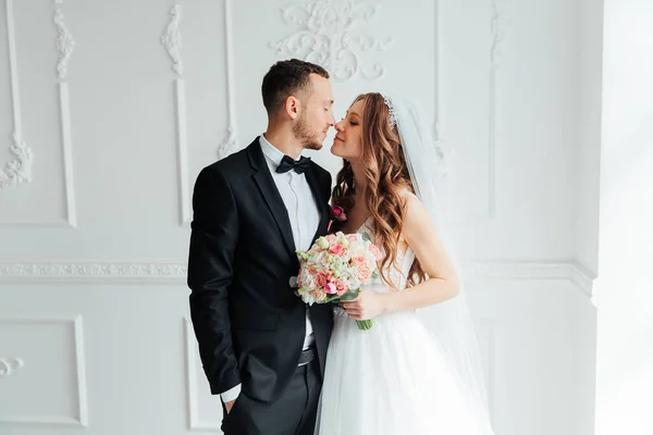 Damadın siyah takım elbiseli ilk buluşması ve beyaz gelinlikli gelinin beyaz ve siyah arka planda bir fotoğraf stüdyosunun içinde bir buket olması.
