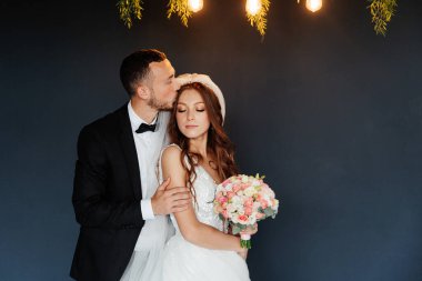 Damadın siyah takım elbiseli ilk buluşması ve beyaz gelinlikli gelinin beyaz ve siyah arka planda bir fotoğraf stüdyosunun içinde bir buket olması.