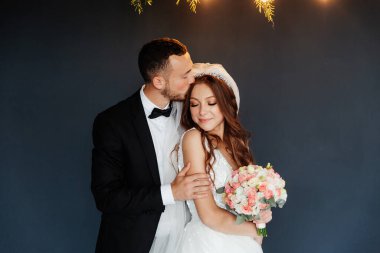 Damadın siyah takım elbiseli ilk buluşması ve beyaz gelinlikli gelinin beyaz ve siyah arka planda bir fotoğraf stüdyosunun içinde bir buket olması.