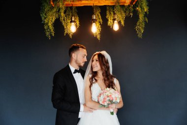 Damadın siyah takım elbiseli ilk buluşması ve beyaz gelinlikli gelinin beyaz ve siyah arka planda bir fotoğraf stüdyosunun içinde bir buket olması.