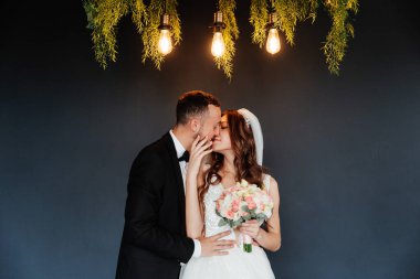 Damadın siyah takım elbiseli ilk buluşması ve beyaz gelinlikli gelinin beyaz ve siyah arka planda bir fotoğraf stüdyosunun içinde bir buket olması.