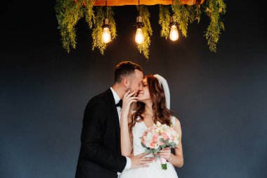 Damadın siyah takım elbiseli ilk buluşması ve beyaz gelinlikli gelinin beyaz ve siyah arka planda bir fotoğraf stüdyosunun içinde bir buket olması.