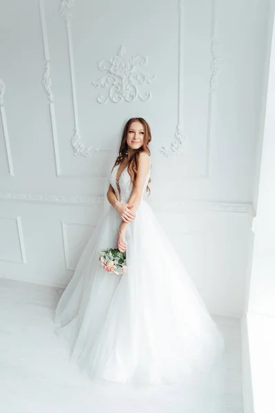 The first meeting of the groom in a black suit and the bride in a white wedding dress with a bouquet in the interior of a photo studio on a white and black background