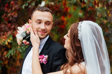 Güzel, lüks bir çiftin düğün yürüyüşü, gelin beyaz bir elbise ve bir buket ve damat açık havada siyah bir takım elbise içinde