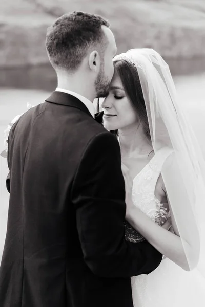 Wedding walk of a beautiful luxurious couple, the bride in a wedding white dress with a bouquet and the groom in a black suit in nature outdoors