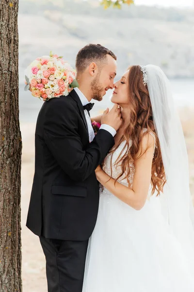 Wedding walk of a beautiful luxurious couple, the bride in a wedding white dress with a bouquet and the groom in a black suit in nature outdoors