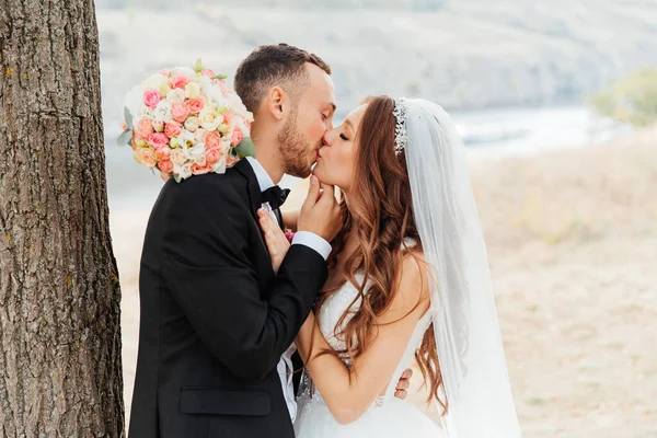 Wedding walk of a beautiful luxurious couple, the bride in a wedding white dress with a bouquet and the groom in a black suit in nature outdoors