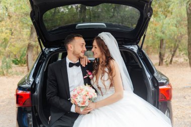 Güzel, lüks bir çiftin düğün yürüyüşü, gelin beyaz bir elbise ve bir buket ve damat açık havada siyah bir takım elbise içinde